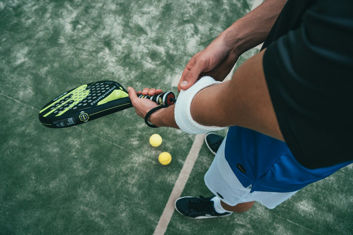 Pala de pádel y pelotas en la pista